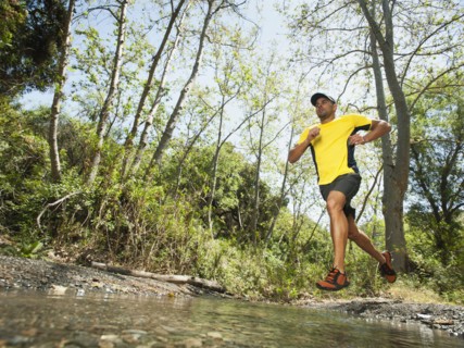 Mixed race man running through stream