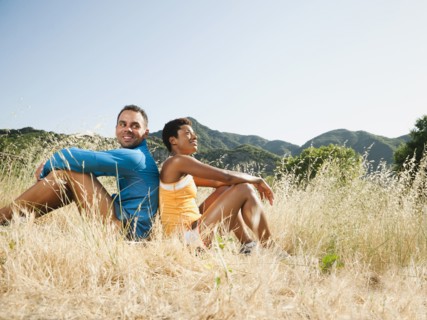 Couple sitting back to back in field after exercise
