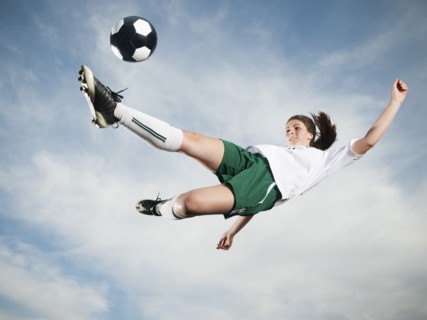 Caucasian teenager kicking soccer ball in mid-air