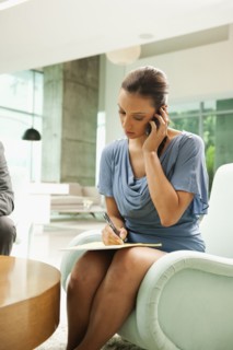 Hispanic businesswoman talking on cell phone in lobby