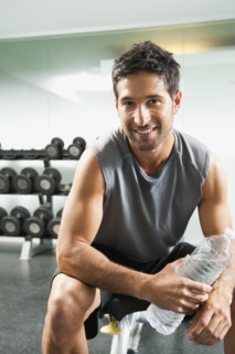 Mixed race man drinking water in gym