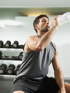 Mixed race man drinking water in gym