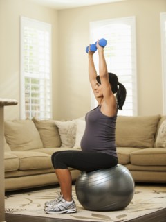 Pregnant Hispanic woman lifting weights
