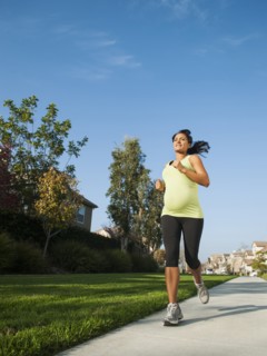 Pregnant Hispanic woman jogging in park