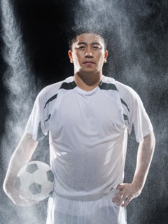 Asian soccer player standing in rain