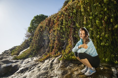 Mixed race woman smiling on rocky beach