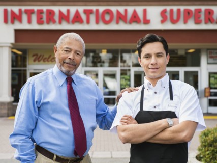 Businessman and worker smiling outside grocery store