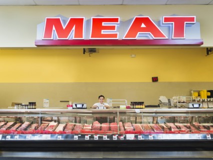 Hispanic butcher at meat counter of grocery store