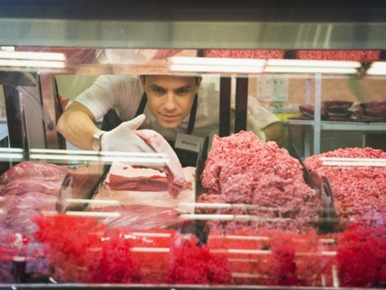 Hispanic butcher at meat counter of grocery store