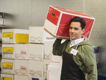 Hispanic worker carrying box in walk-in freezer