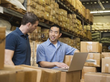 Workers using laptop in textile factory