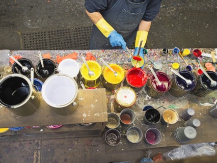 Hispanic worker mixing paint in workshop