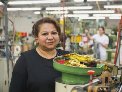 Hispanic worker operating machinery in textile factory