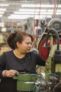 Hispanic worker operating machinery in textile factory