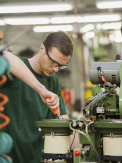 Caucasian worker operating machinery in textile factory