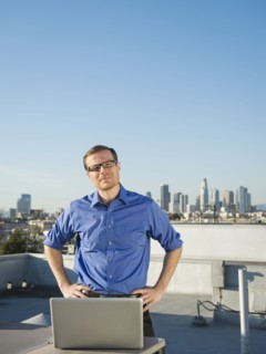 Caucasian businessman using laptop on urban rooftop