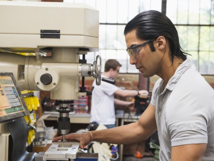 Workers using machinery in machine shop