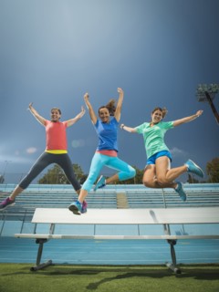 Caucasian women jumping for joy in stadium