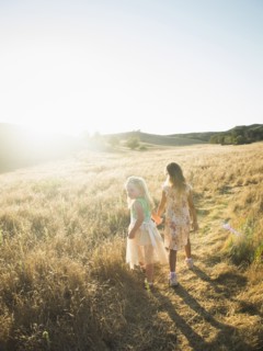 Caucasian girls holding hands in rural field