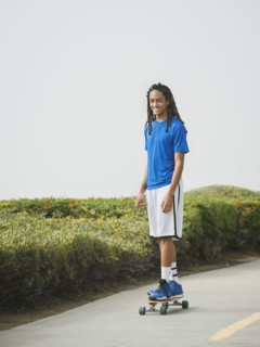 Black teenage boy riding skateboard on street