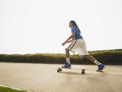 Black teenage boy riding skateboard on street