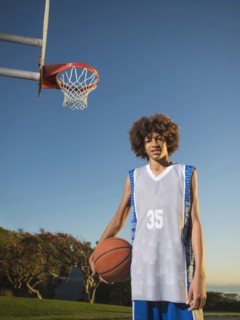 Black teenage boy holding basketball on court
