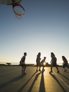 Back lit basketball teams playing on court