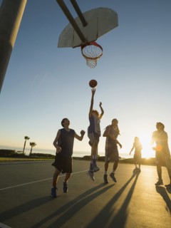 Back lit basketball teams playing on court