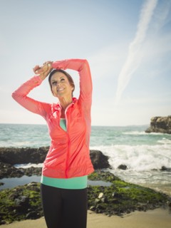 Caucasian runner stretching on beach