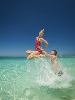 Caucasian couple playing in water in tropical ocean