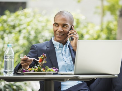 Black businessman working and eating lunch outdoors
