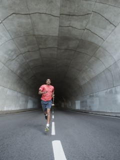 Black man running in urban tunnel