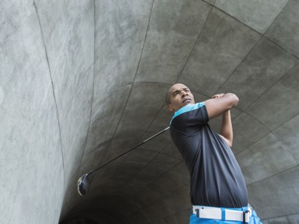 Black man playing golf in urban tunnel