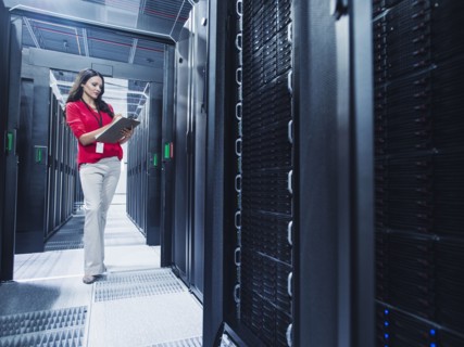 Caucasian businesswoman reading clipboard in server room