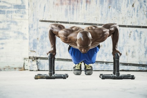 Black man doing push ups in warehouse