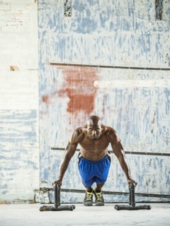 Black man doing push ups in warehouse