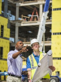 Businessman and construction worker reading blueprints at construction site