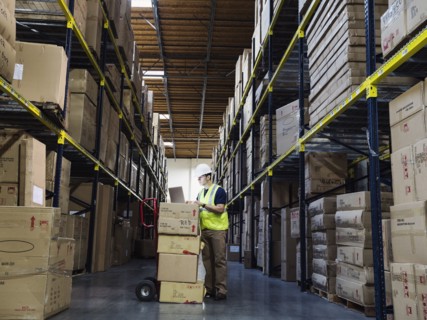 Caucasian worker using laptop in warehouse