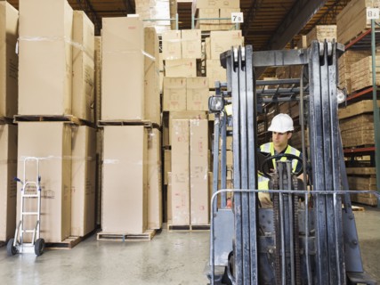 Caucasian worker driving forklift in warehouse