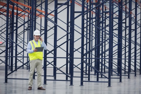 Caucasian worker using digital tablet in empty warehouse