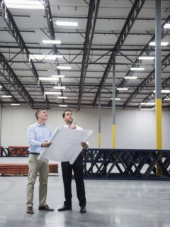 Caucasian architects reading blueprints in warehouse
