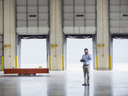 Caucasian businessman talking on cell phone in warehouse