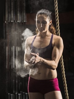 Caucasian athlete chalking her hands in gym