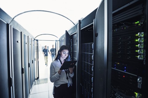 Technician using digital tablet in server room