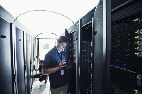 Technician using digital tablet in server room