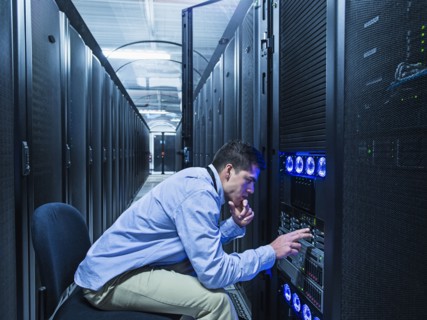 Hispanic technician checking technology in server room