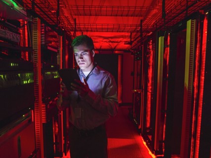Hispanic technician using digital tablet in server room