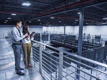 Business people examining server room from balcony