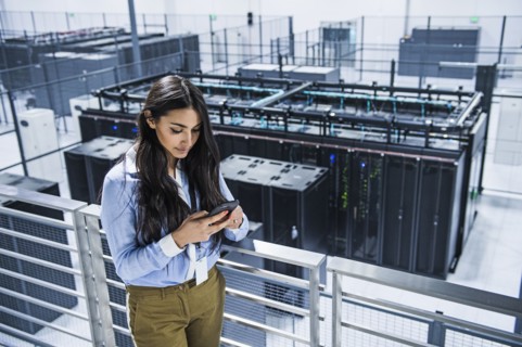 Mixed race businesswoman using cell phone on balcony over server room