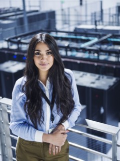 Mixed race businesswoman smiling on balcony over server room